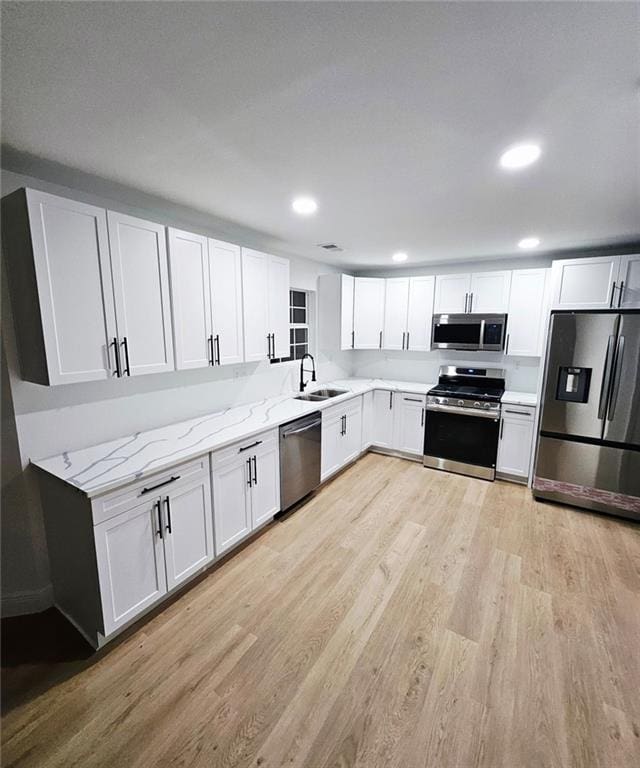 681 Burtons Cv, Hampton, GA 30228 - kitchen with appliances with stainless steel finishes, light wood finished floors, a sink, light stone counters, and recessed lighting
