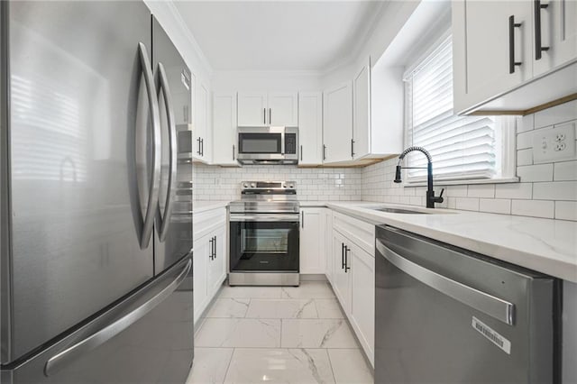 kitchen featuring appliances with stainless steel finishes, a sink, light marble finish floors, light stone countertops, and white cabinets