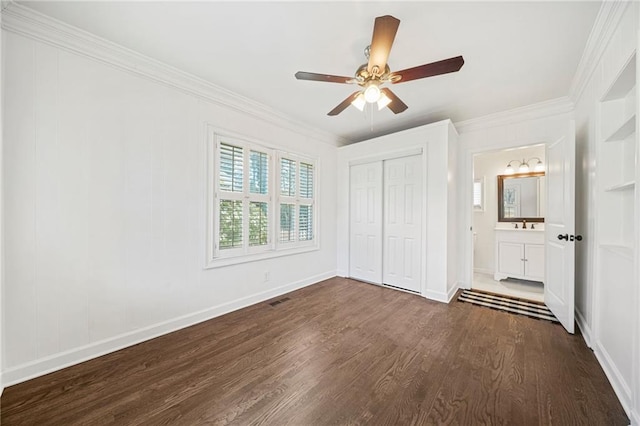 unfurnished bedroom featuring dark wood-style flooring, ornamental molding, a closet, and baseboards