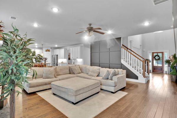 kitchen featuring appliances with stainless steel finishes, an island with sink, white cabinets, dark hardwood / wood-style flooring, and pendant lighting