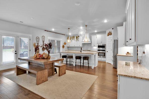 kitchen with stainless steel appliances, white cabinets, a center island with sink, and dark hardwood / wood-style flooring