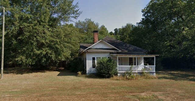 view of property exterior featuring covered porch and a yard