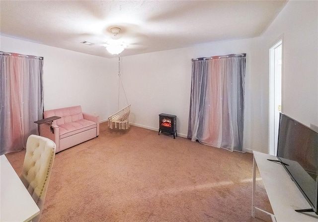 sitting room featuring carpet flooring and a wood stove