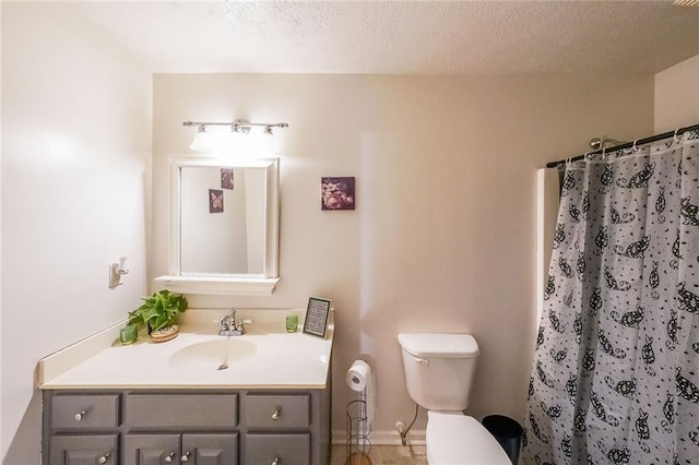 bathroom with a shower with curtain, vanity, toilet, and a textured ceiling