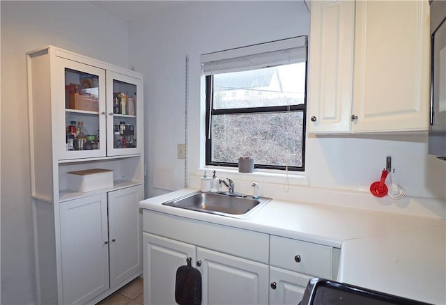 kitchen featuring white cabinetry, sink, tile patterned floors, and range