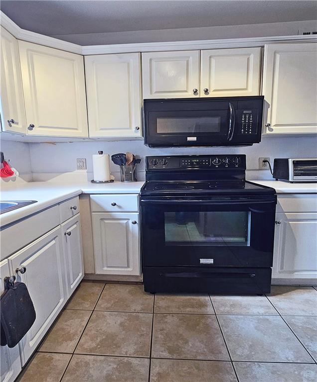 kitchen with light tile patterned floors, white cabinets, and black appliances