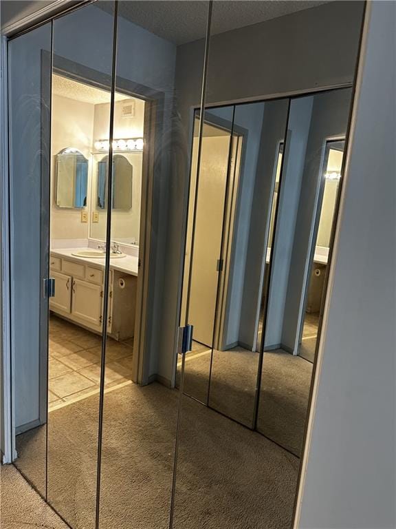 corridor with light colored carpet and a textured ceiling