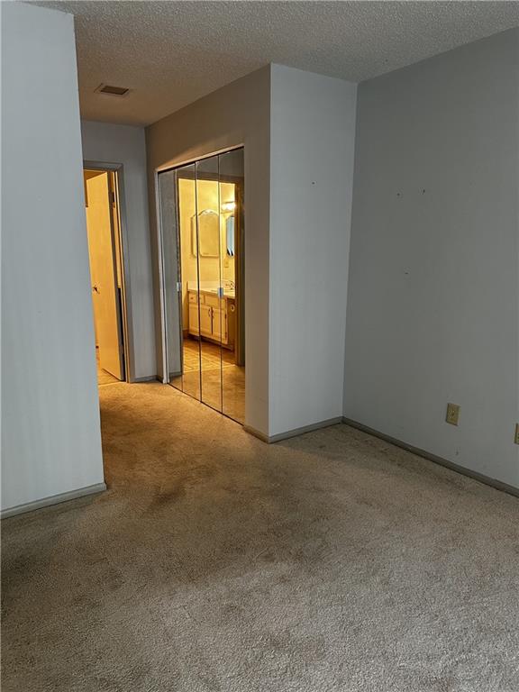 empty room with a textured ceiling and light carpet