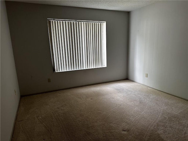 empty room with light carpet and a textured ceiling