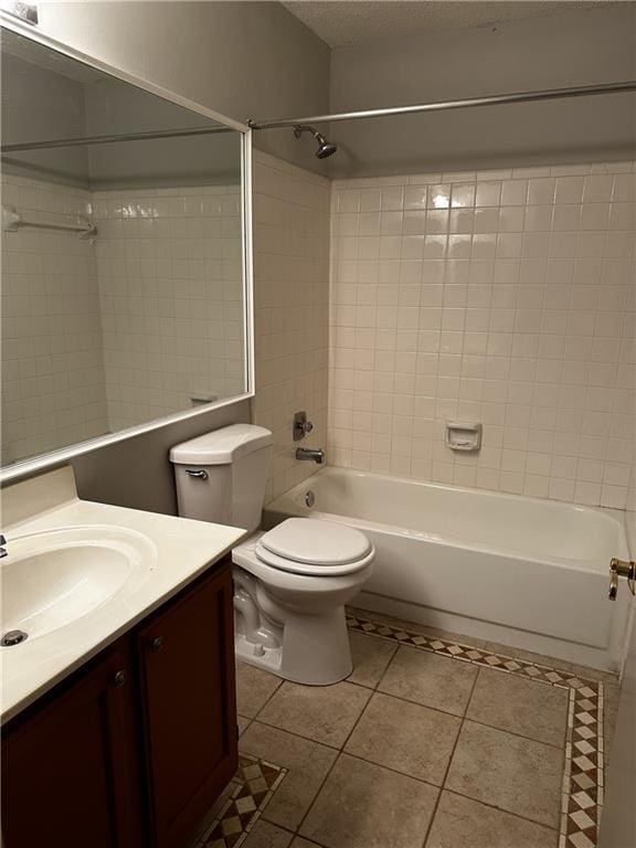 full bathroom with tile patterned floors, a textured ceiling, toilet, vanity, and tiled shower / bath