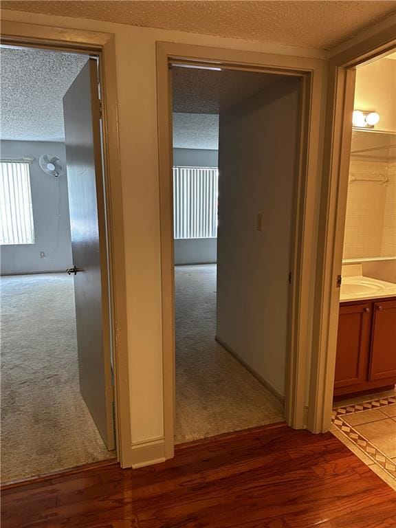 corridor featuring dark colored carpet and a textured ceiling