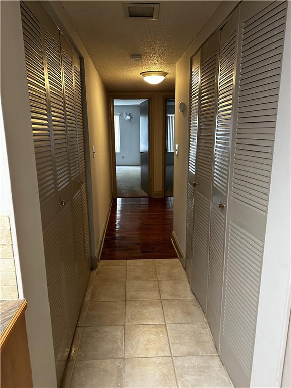 corridor featuring light tile patterned floors and a textured ceiling