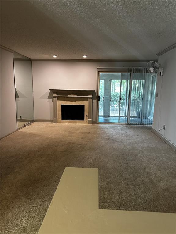 unfurnished living room with carpet floors, a textured ceiling, and a tiled fireplace