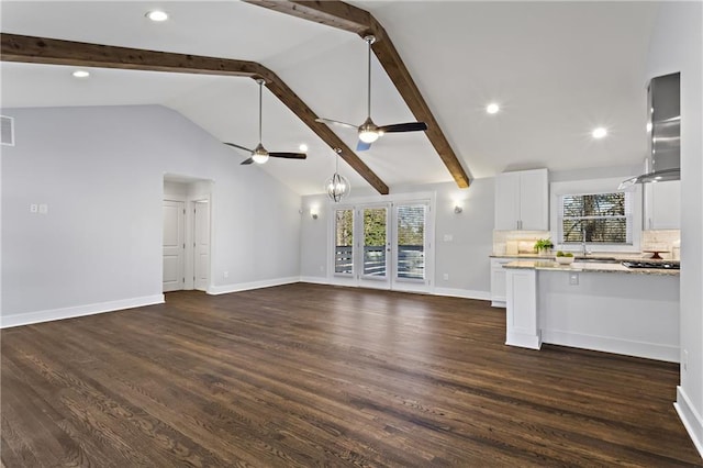 unfurnished living room with dark wood finished floors, lofted ceiling with beams, and plenty of natural light