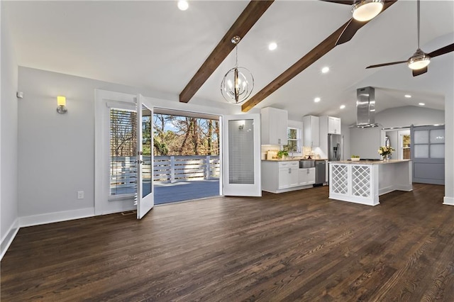 unfurnished living room featuring a barn door, plenty of natural light, dark wood-style floors, and vaulted ceiling with beams