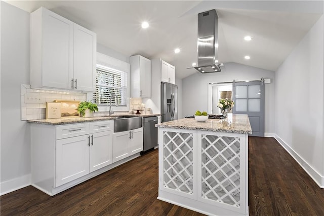 kitchen with lofted ceiling, appliances with stainless steel finishes, a barn door, exhaust hood, and a center island