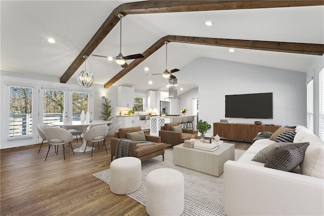 living area featuring lofted ceiling with beams, light wood-style flooring, recessed lighting, and ceiling fan with notable chandelier