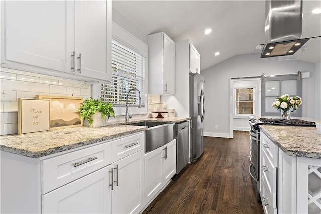 kitchen with backsplash, wall chimney range hood, appliances with stainless steel finishes, white cabinets, and a sink