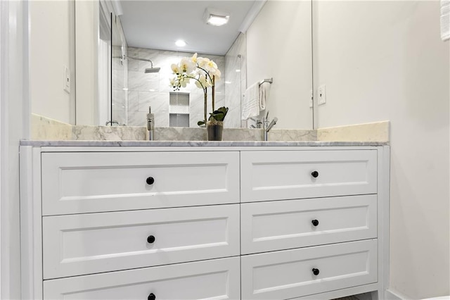 bathroom with double vanity, tiled shower, and a sink