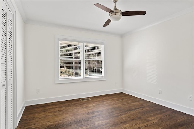 spare room featuring visible vents, crown molding, dark wood-type flooring, and baseboards