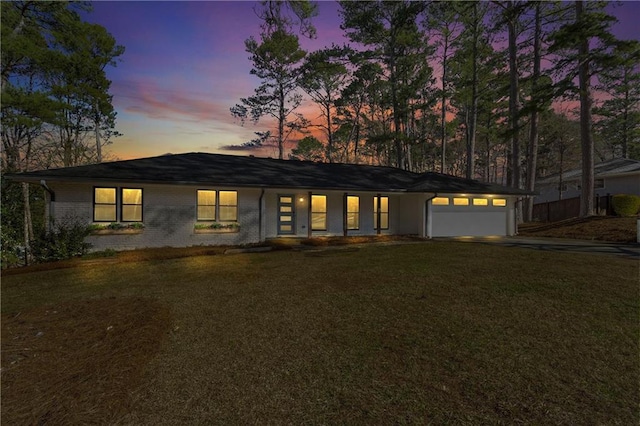 mid-century home with brick siding, a lawn, and a garage