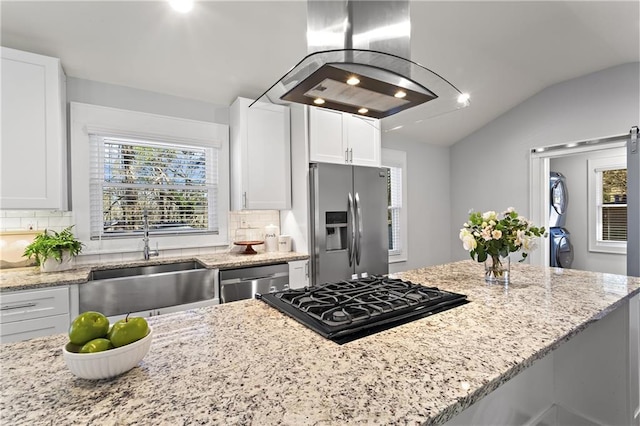 kitchen with island exhaust hood, a sink, appliances with stainless steel finishes, white cabinets, and stacked washer / drying machine