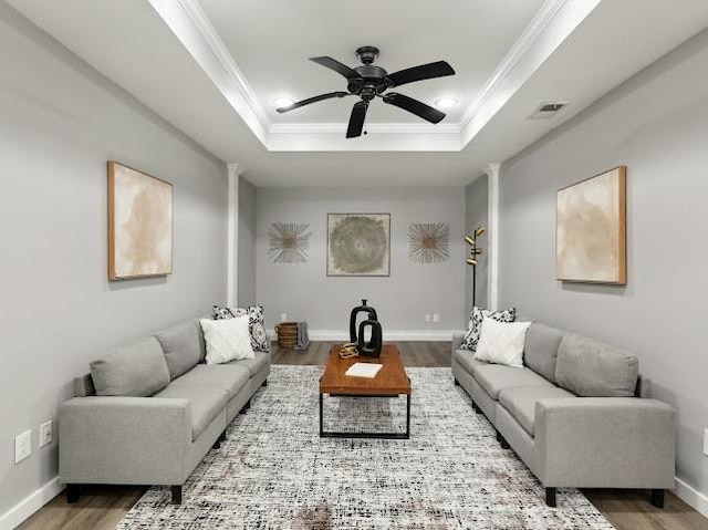 living room featuring visible vents, crown molding, wood finished floors, a raised ceiling, and a ceiling fan