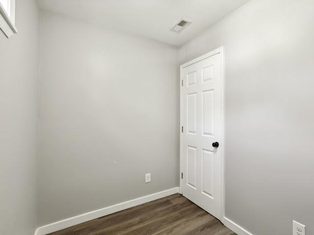 empty room featuring visible vents, baseboards, and dark wood-style flooring