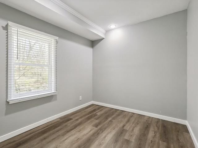 spare room with dark wood-type flooring and baseboards