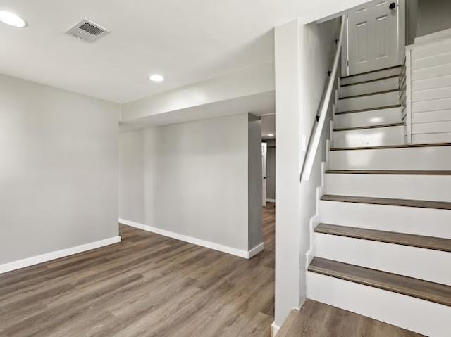 below grade area featuring visible vents, wood finished floors, recessed lighting, stairway, and baseboards