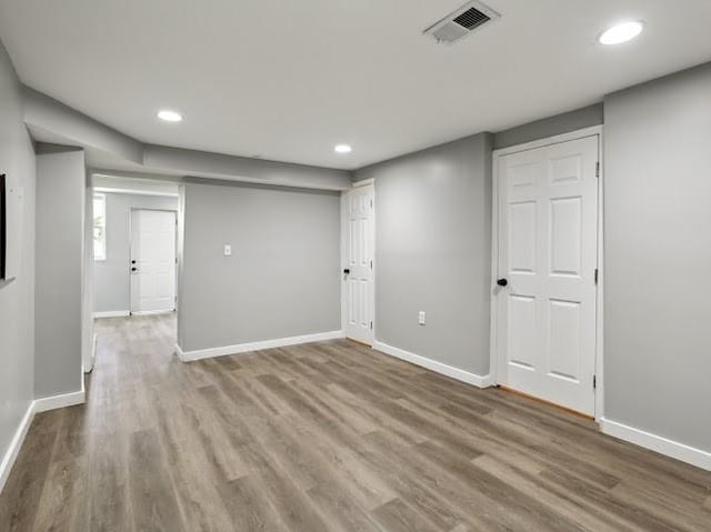 empty room with recessed lighting, wood finished floors, visible vents, and baseboards