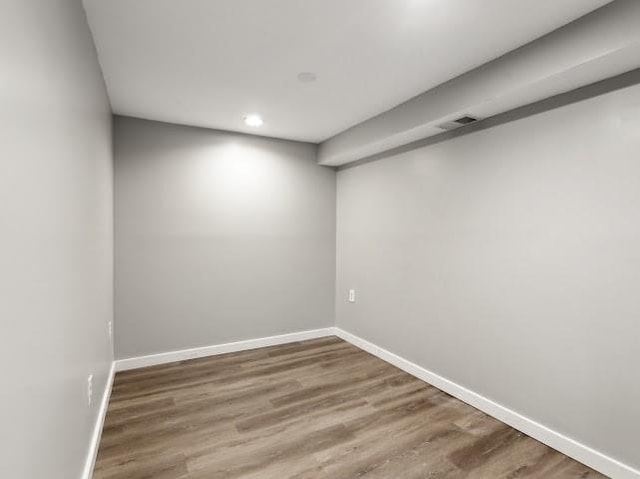 empty room featuring visible vents, baseboards, and wood finished floors