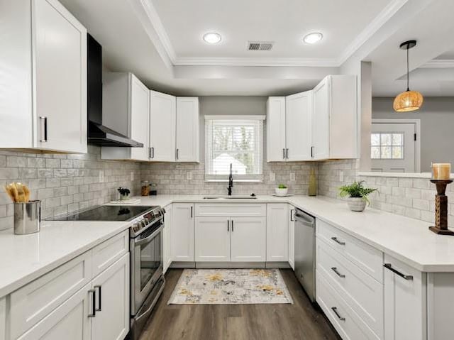 kitchen with visible vents, dark wood finished floors, appliances with stainless steel finishes, wall chimney exhaust hood, and a sink