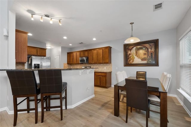 kitchen featuring appliances with stainless steel finishes, a breakfast bar, pendant lighting, dark stone counters, and kitchen peninsula