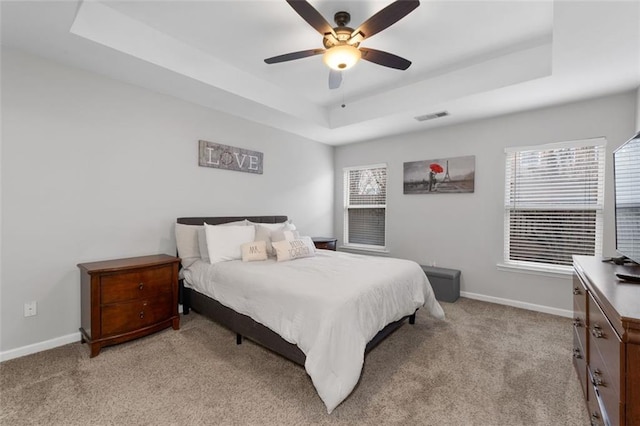 carpeted bedroom featuring a tray ceiling and ceiling fan