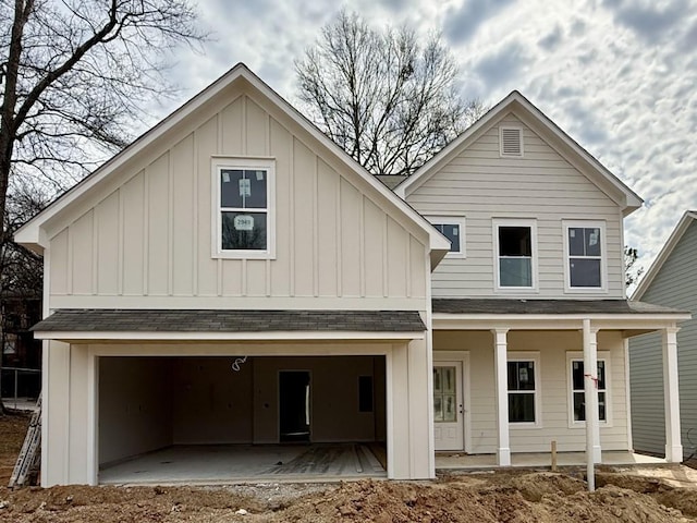 view of front of house with board and batten siding, a patio area, a garage, and a shingled roof