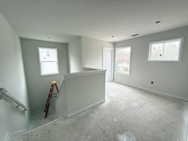 spare room featuring a wealth of natural light, visible vents, and baseboards