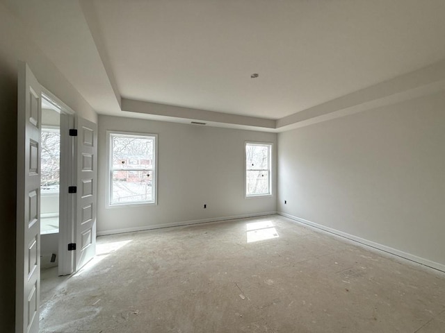 empty room with baseboards and a raised ceiling