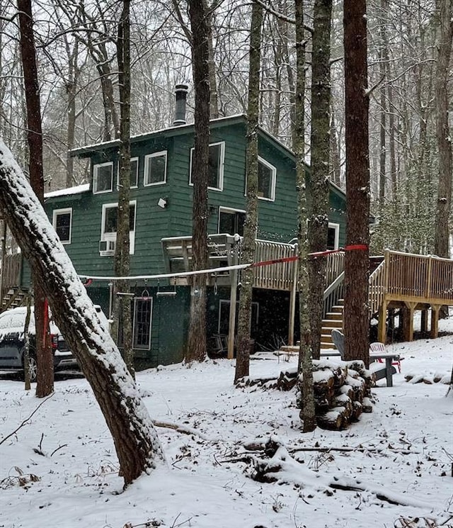 snow covered property with stairway and a wooden deck