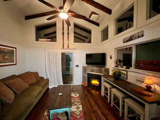 living area featuring lofted ceiling with beams, a ceiling fan, wood finished floors, wooden ceiling, and a tiled fireplace