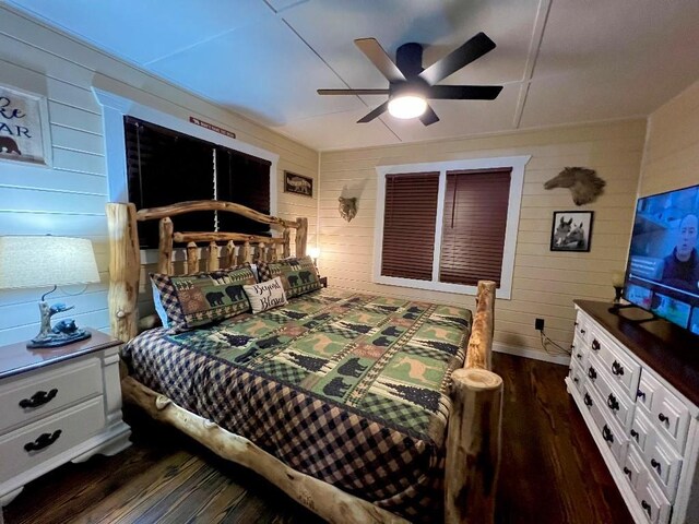 bedroom featuring wooden walls, ceiling fan, and dark wood finished floors