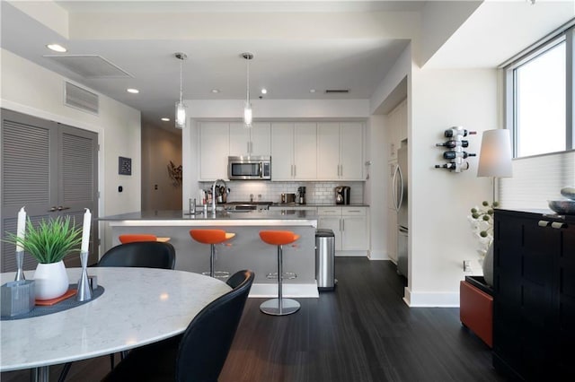 1100 Howell Mill Rd NW Unit 708, Atlanta, GA 30318 - kitchen featuring stainless steel appliances, backsplash, dark wood-type flooring, white cabinetry, and an island with sink