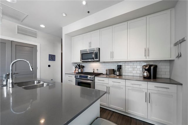 1100 Howell Mill Rd NW Unit 708, Atlanta, GA 30318 - kitchen with appliances with stainless steel finishes, dark countertops, white cabinets, backsplash, and dark wood-type flooring