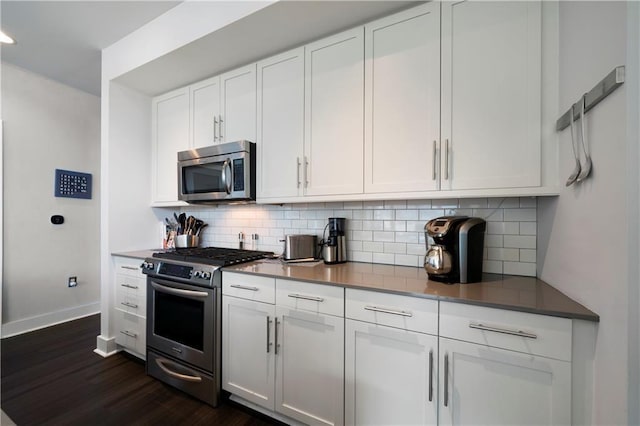 1100 Howell Mill Rd NW Unit 708, Atlanta, GA 30318 - kitchen featuring stainless steel appliances, dark wood-style floors, white cabinets, backsplash, and dark countertops