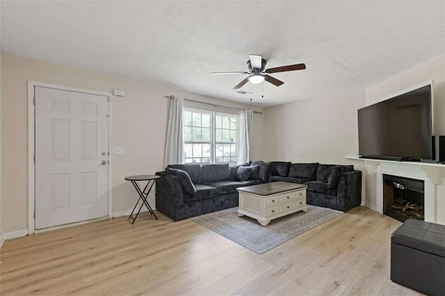 1450 Steam Engine Way, Conyers, GA 30013 - living area with a ceiling fan, light wood-type flooring, a textured ceiling, a fireplace, and baseboards