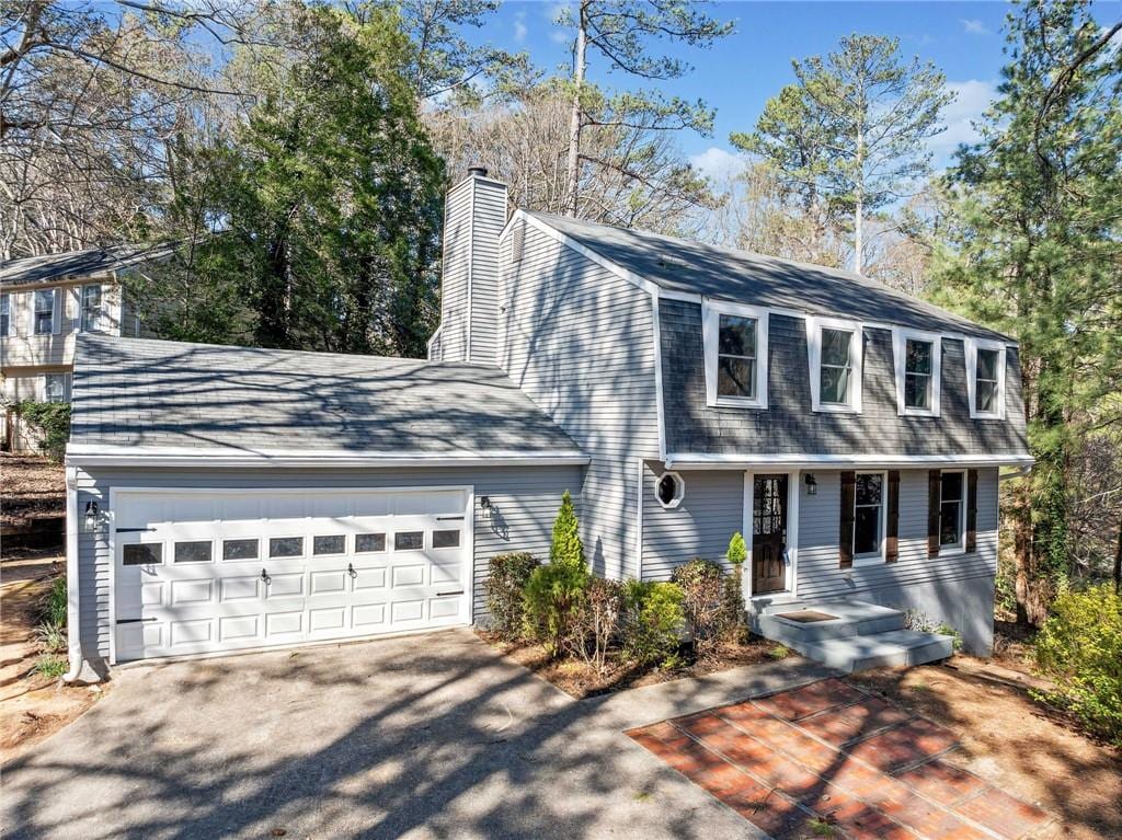 195 Sailwind Ct, Roswell, GA 30076 - view of front facade with an attached garage, driveway, a gambrel roof, and a chimney