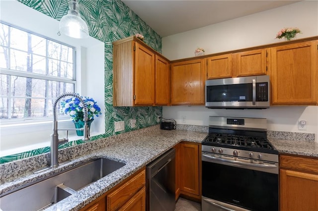 kitchen featuring appliances with stainless steel finishes, sink, and light stone counters