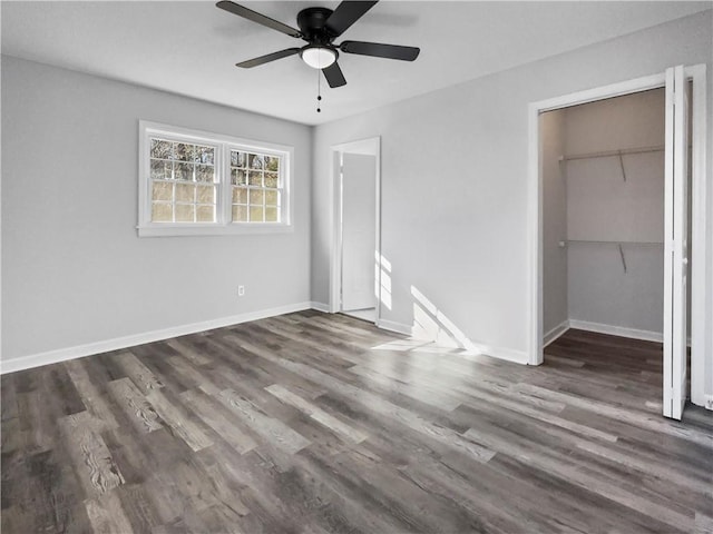 unfurnished bedroom featuring dark wood-type flooring, a walk in closet, ceiling fan, and a closet