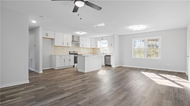 kitchen featuring white cabinetry, a center island, wall chimney exhaust hood, dark hardwood / wood-style floors, and appliances with stainless steel finishes