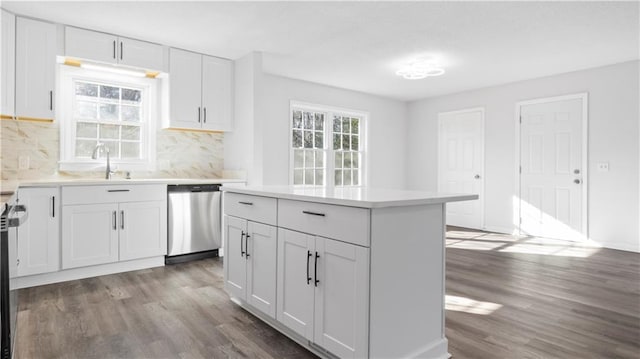 kitchen with white cabinets, stainless steel dishwasher, a kitchen island, and tasteful backsplash